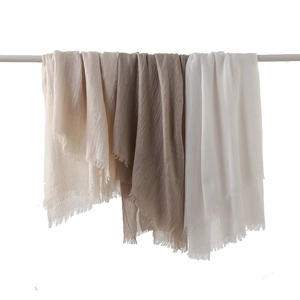 Linen and cotton scarf in neutral tones with frayed edges and lightweight texture