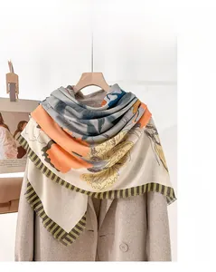 Detail of floral printed wool scarf with delicate fringe paired with a beige coat