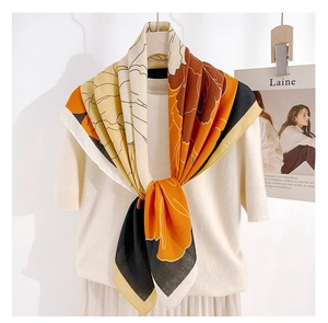 Detailed close-up of floral print silk scarf with orange and beige color block pattern