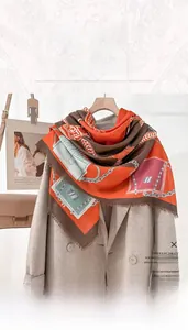 Detail of large fringe square scarf with orange chain print styled on a wool coat