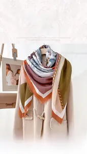 Detail of elegant floral print scarf with frayed edges draped over a stylish beige coat