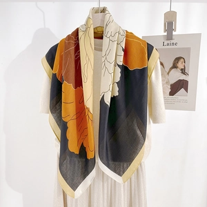 Elegant floral print silk scarf in mustard yellow and brown on a white wooden hanger