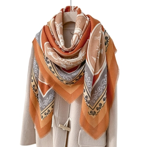 Vintage bohemian square shawl with ethnic patterns and fringe, styled on a beige coat