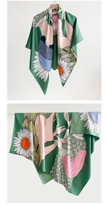 Détail d'un foulard en soie vert avec motifs de marguerites suspendu sur un cintre en bois