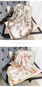 Detail of floral and ginkgo leaf patterns on silk scarves draped over a grey armchair