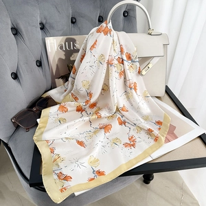 Ivory square silk scarf with orange floral prints styled on a white leather handbag