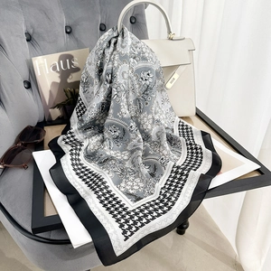 Elegant floral and houndstooth print scarf draped on a luxury handbag in a chic setting