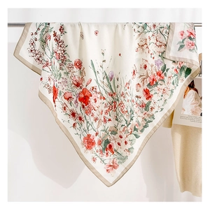 Detailed view of square silk scarf with floral patterns hanging on a rack