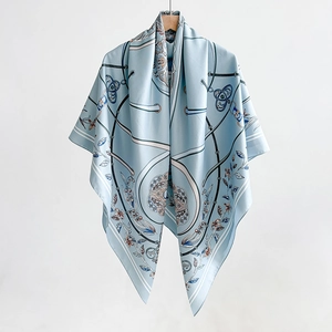 Blue silk scarf with elegant chain and floral print hanging on a wooden hanger
