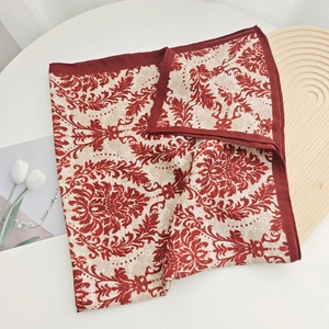 Detailed macro shot of vintage floral pattern on a burgundy silk scarf with red edges