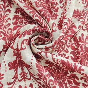 Macro shot of floral silk scarf featuring red damascus patterns on beige fabric texture