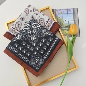 Detail of vintage paisley cotton-linen scarves in beige and navy folded on a gold tray