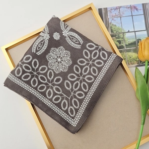 Detailed texture of brown square scarf with paisley patterns and white mandala prints