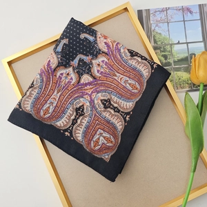 Elegant black paisley square silk scarf with orange and purple patterns on a creative background