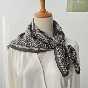 Elegant dark brown geometric pattern silk scarf tied on mannequin in soft lighting