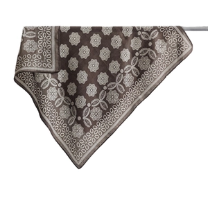 Brown silk scarf with white floral embroidery and geometric border on a display bar