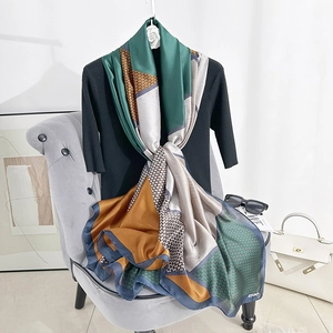 Elegant geometric color-block silk scarf with houndstooth pattern displayed on a chair