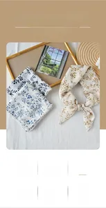 Detail of printed square scarf showing elegant floral patterns and scalloped wave edges