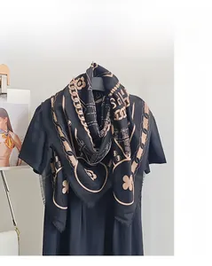 Détail d'une écharpe en laine mercerisée avec motifs chaînes dorées et bords à franges fines