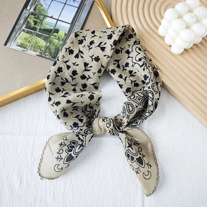 Vintage paisley print silk square scarf in light khaki shown on a wooden display tray