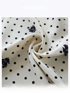 Close-up of premium twill satin fabric with black polka dots and floral patterns