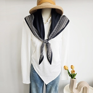 Elegant black and white paisley print satin neck scarf styled with a knot on a mannequin