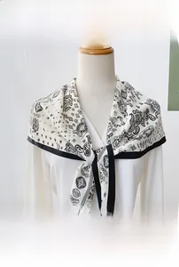 Détail d'un foulard triangle en soie blanche avec motif cachemire et bordure noire