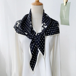 Elegant black polka dot silk scarf with white floral print on a white shirt model