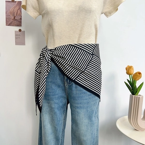 Black and white striped scarf styled as a chic waist accessory on blue denim jeans