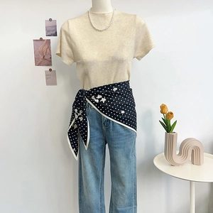 Elegant polka dot neckerchief styled with a beige knit top and vintage blue jeans outfit