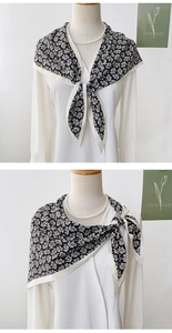 Detailed close-up of a black and white paisley print silk scarf styled on a model