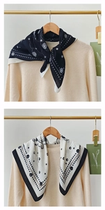 Detail of vintage floral silk scarf styled on beige sweater with golden hanger