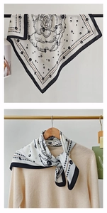 Detail of floral polka dot silk scarf with black borders worn on a beige sweater