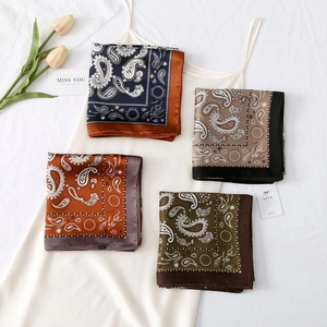 Close-up of four classic paisley patterned silk-like scarves neatly folded on a white dress