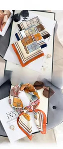 Dettaglio di un foulard in seta con stampa geometrica colorata annodato con stile