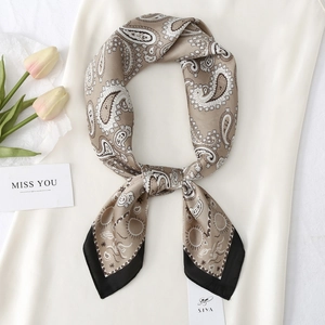 Detailed view of khaki paisley satin scarf with black border on fabric background