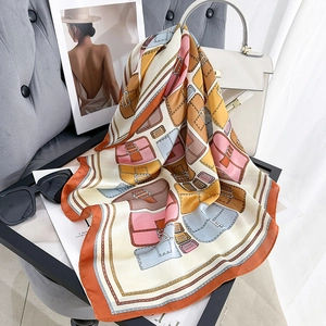 Foulard quadrato in seta con stampe di borse vintage e catene su divano moderno