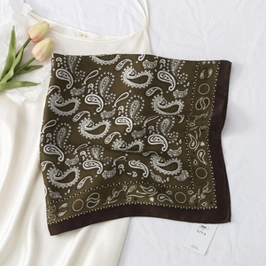 Classic olive green paisley silk scarf elegantly draped over a white satin dress