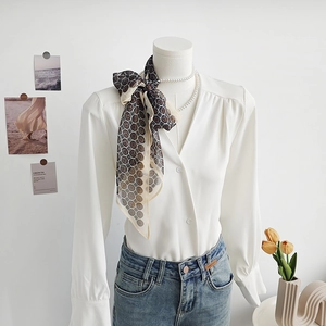Elegante camicetta in chiffon bianco con sciarpa geometrica e jeans blu attillati