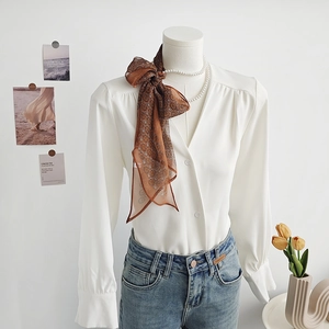 Elegante camicia in chiffon bianco con sciarpa stampata e jeans su un manichino