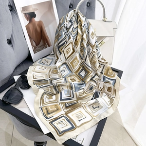 Modern abstract geometric pattern silk scarf with earth tones on elegant gray chair