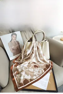 Vue détaillée d'un foulard carré en satin fleuri drapé sur un sac à main en cuir