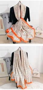 Détail d'un foulard en soie élégant avec imprimé géométrique, bord orange et fini satiné