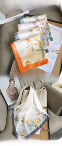 Close-up of floral silk scarves in multiple colors paired with a beige leather handbag