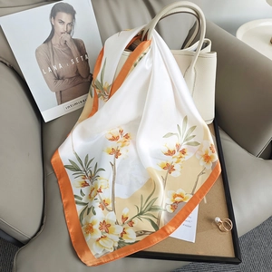 Elegant floral silk square scarf in orange and cream draped on a stylish handbag