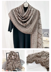 Detail view of coffee brown shawl with white lace floral print on soft fabric texture