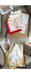 Gros plan de foulards en soie floraux avec bordures colorées noués sur un sac à main