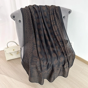 Elegant black shawl with vintage brown mandala print draped on a chair for travel