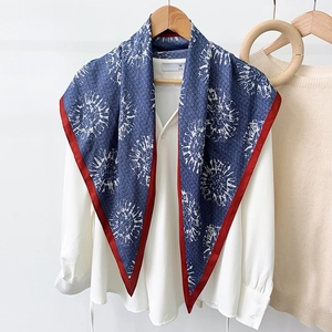 Blue triangle scarf with white radial patterns and red borders over a white shirt