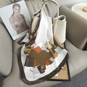 Elegant leopard and polka dot print silk scarf draped over a luxury white leather bag